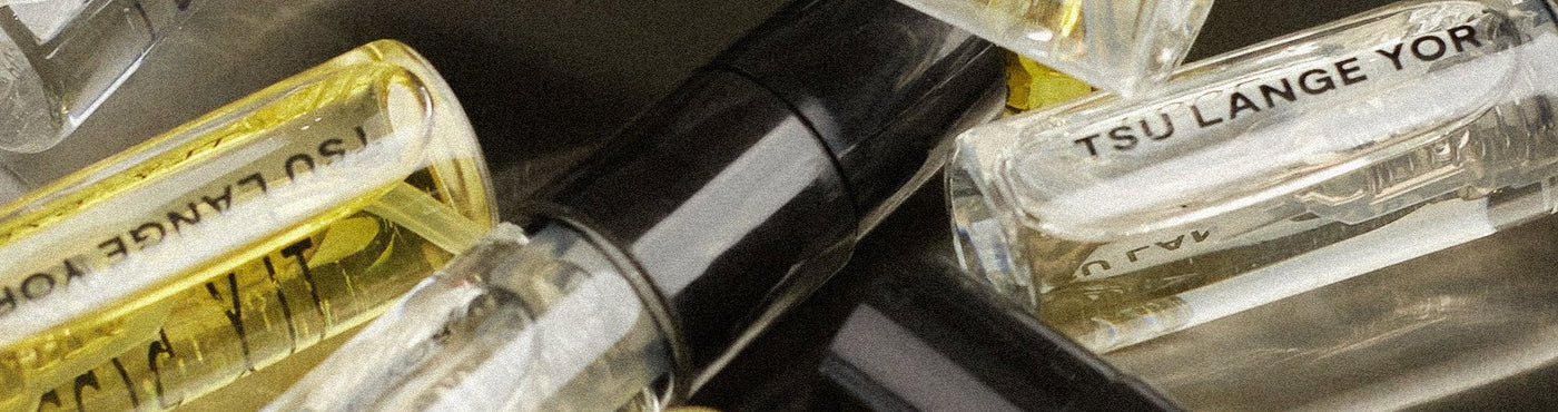 A collection of small, clear glass vials filled  different samples of fragrances from the TSU LANGE YOR fragrance collection.